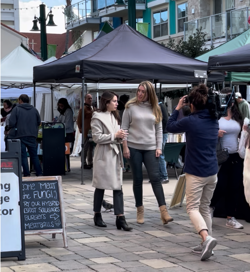 Loretta Markevics being filmed walking through a farmers' market for The Farmers Finds