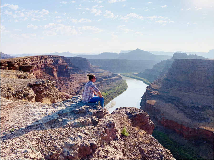Loretta Markevics sitting on a canyon ledge overlooking the Colorado River