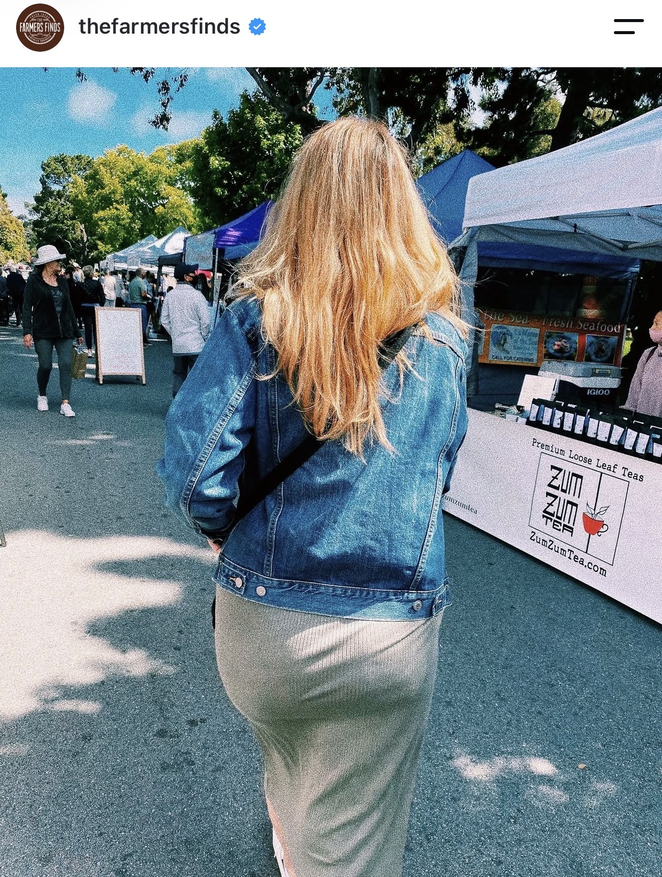 Loretta Markevics walking a farmers' market lined with vendor tents
